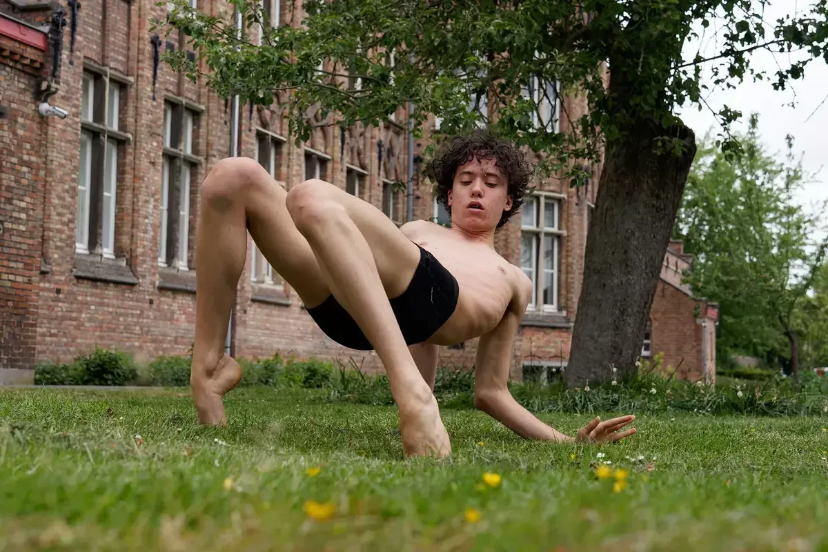 Ben is een blanke man met zwart, krullend haar. Hij draagt een zwart shortje. Ben danst op het gras in een park.